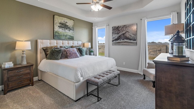 carpeted bedroom with ceiling fan and a tray ceiling