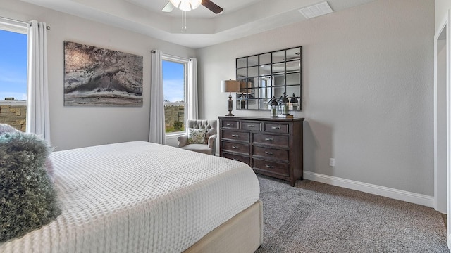 bedroom featuring a raised ceiling, ceiling fan, and carpet flooring