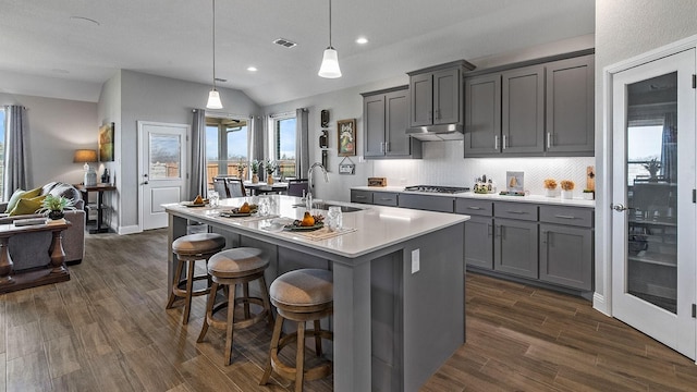 kitchen featuring sink, decorative light fixtures, a kitchen breakfast bar, gray cabinets, and a kitchen island with sink