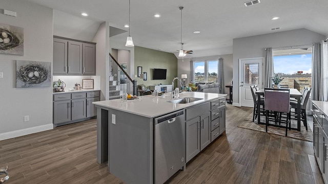 kitchen featuring decorative light fixtures, sink, gray cabinetry, stainless steel dishwasher, and a center island with sink