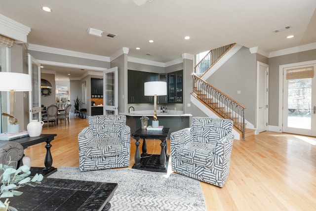 living room featuring ornamental molding, sink, and light hardwood / wood-style floors