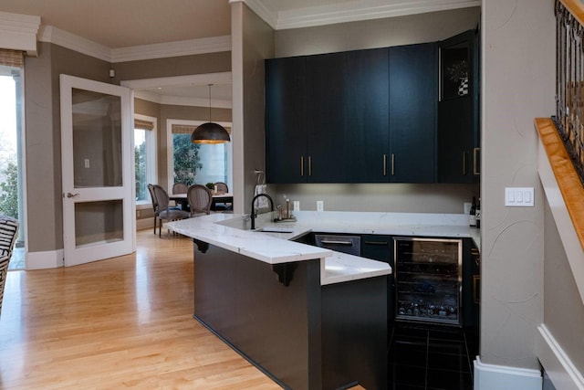 kitchen with sink, decorative light fixtures, light wood-type flooring, a kitchen breakfast bar, and kitchen peninsula