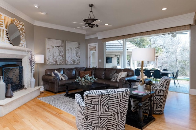 living room featuring hardwood / wood-style flooring, a high end fireplace, ornamental molding, and ceiling fan