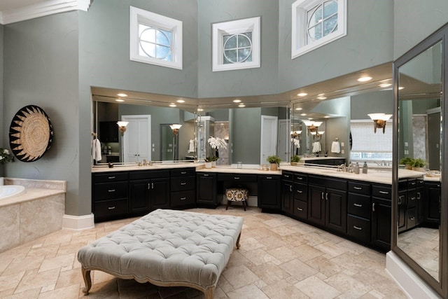 bathroom with tiled tub, vanity, and a high ceiling