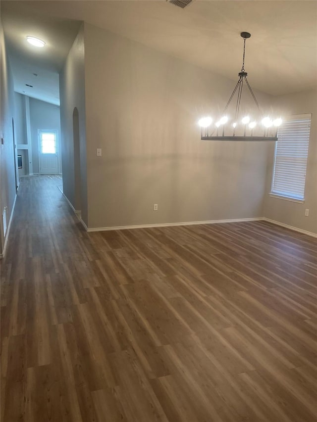 unfurnished dining area with dark wood-type flooring and an inviting chandelier