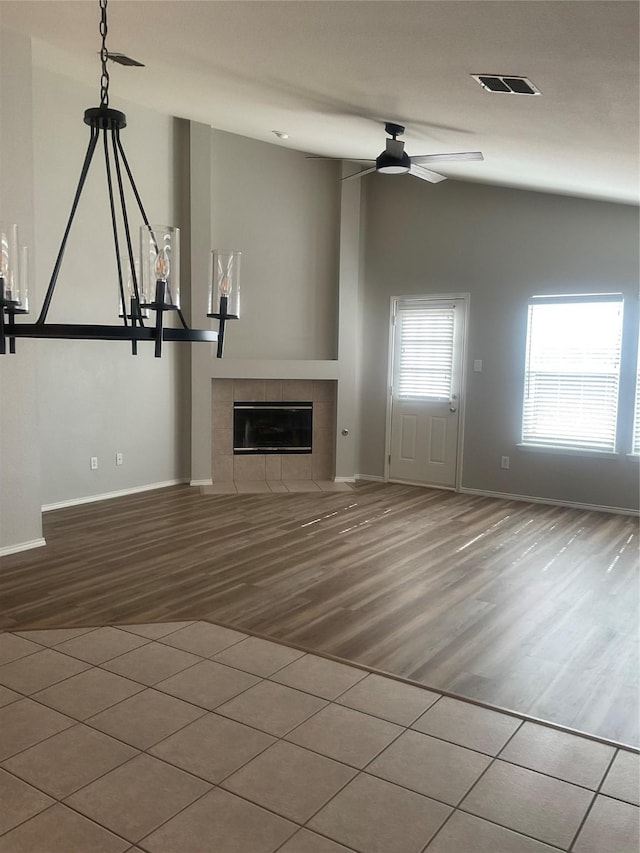 unfurnished living room featuring ceiling fan, a fireplace, vaulted ceiling, and hardwood / wood-style floors