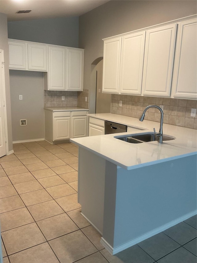 kitchen featuring light tile patterned floors, dishwasher, kitchen peninsula, and white cabinets