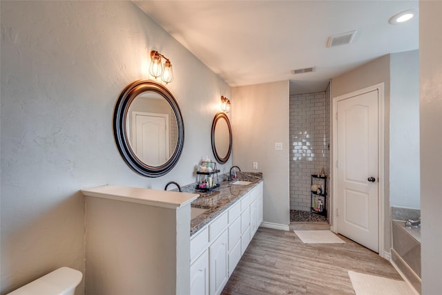 bathroom with wood-type flooring, vanity, and plus walk in shower