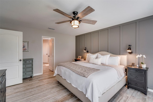 bedroom with light wood-style floors, visible vents, ceiling fan, and baseboards