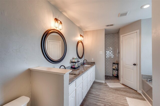 bathroom with wood-type flooring, toilet, a bath, and vanity