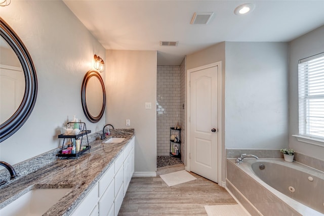 full bath with visible vents, a sink, and a jetted tub