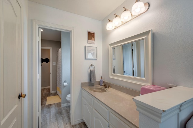 bathroom featuring baseboards, vanity, toilet, and wood finished floors