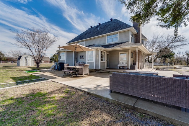 back of house with outdoor lounge area, a storage shed, an outdoor structure, and a patio