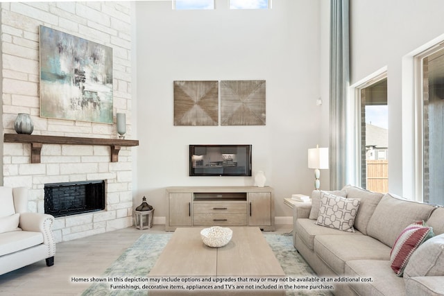 living room featuring a stone fireplace and light wood-type flooring