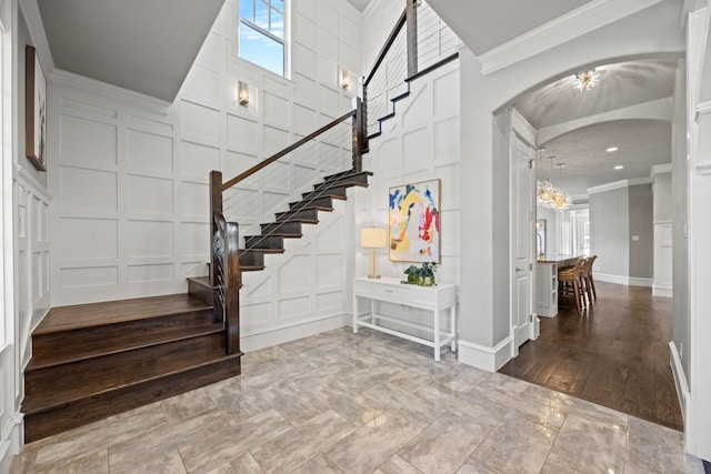 stairs with a notable chandelier and ornamental molding