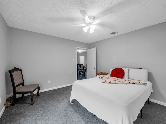 bedroom with ceiling fan, dark carpet, and a textured ceiling