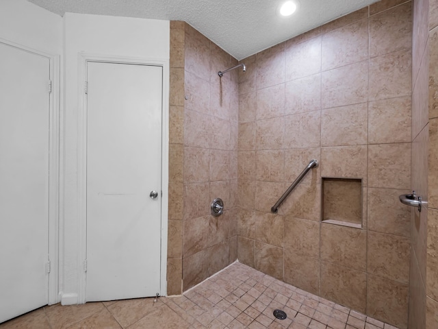 bathroom with a textured ceiling, tile patterned floors, and tiled shower