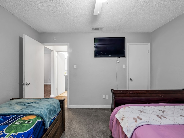 carpeted bedroom featuring ceiling fan and a textured ceiling