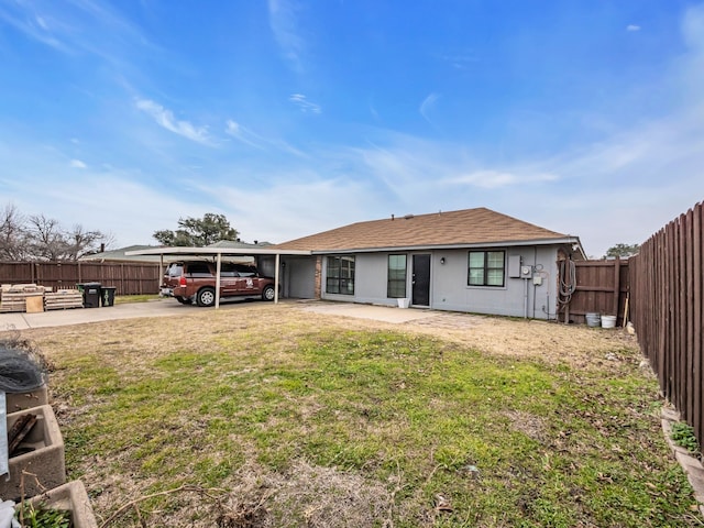 rear view of property featuring a carport and a yard