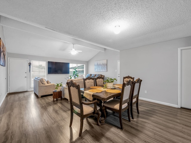 dining space featuring ceiling fan, dark hardwood / wood-style floors, a textured ceiling, and vaulted ceiling with beams