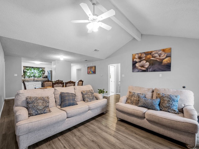 living room with hardwood / wood-style flooring, ceiling fan, lofted ceiling with beams, and a textured ceiling