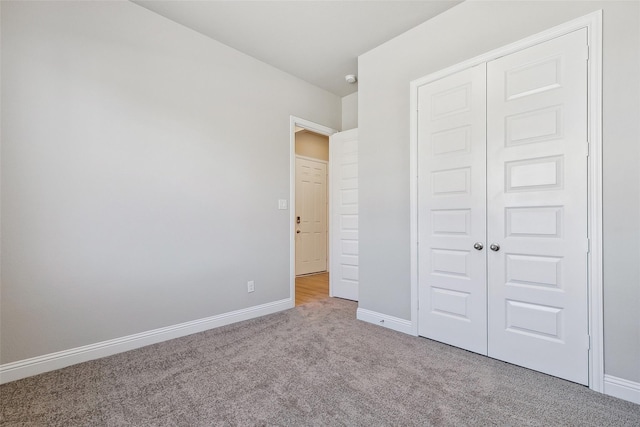 unfurnished bedroom with light colored carpet and a closet