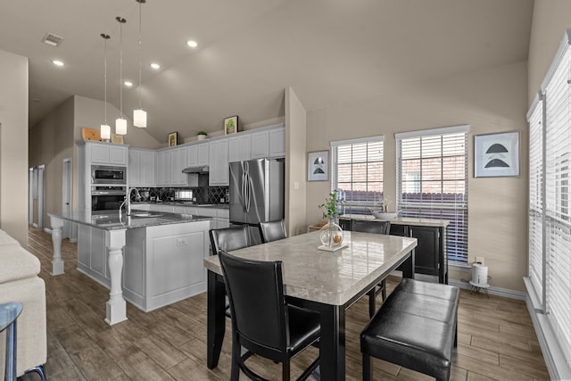 kitchen featuring sink, a breakfast bar area, decorative light fixtures, stainless steel appliances, and a kitchen island with sink