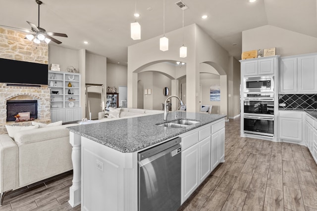 kitchen featuring stainless steel appliances, an island with sink, sink, and white cabinets