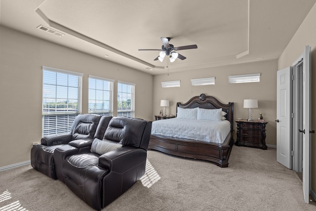 carpeted bedroom featuring a tray ceiling and ceiling fan