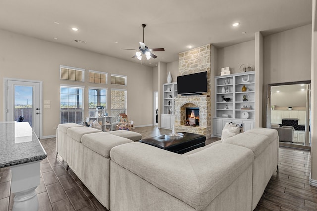 living room featuring ceiling fan, a towering ceiling, and a fireplace