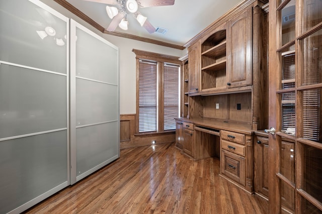 home office with crown molding, built in desk, dark hardwood / wood-style floors, and ceiling fan