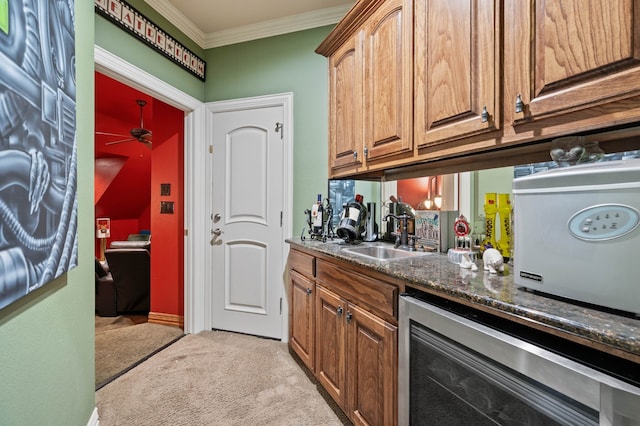 bar with sink, dark stone countertops, ornamental molding, ceiling fan, and light carpet