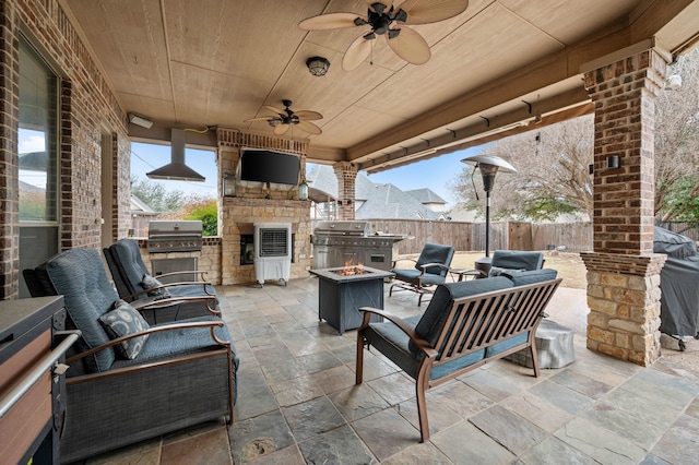 view of patio / terrace with a grill, an outdoor living space with a fireplace, ceiling fan, and exterior kitchen