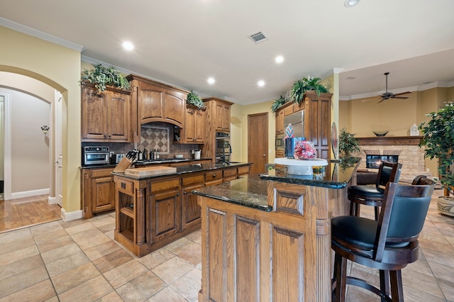 kitchen featuring tasteful backsplash, crown molding, a kitchen island with sink, and a breakfast bar area