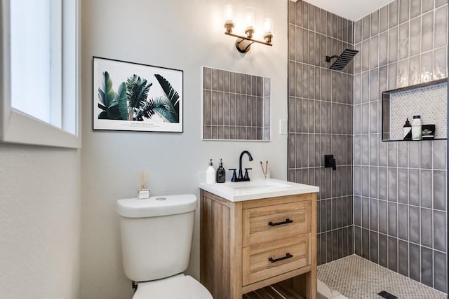 bathroom with vanity, toilet, and a tile shower