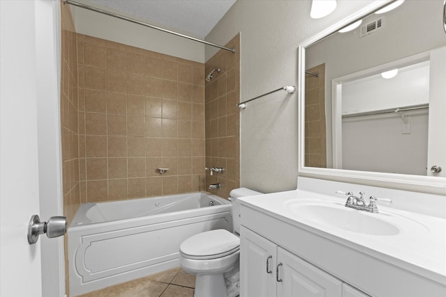 full bathroom featuring tile patterned flooring, tiled shower / bath, vanity, and toilet