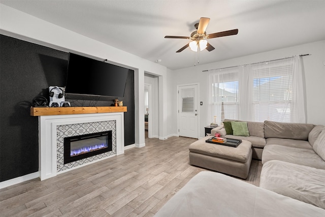 living room featuring ceiling fan, a fireplace, and light hardwood / wood-style floors