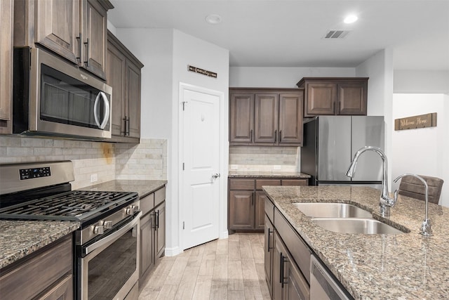 kitchen featuring stainless steel appliances, sink, and light stone counters