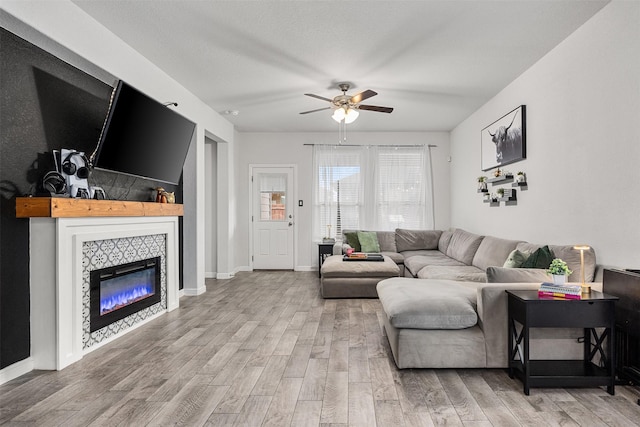 living room with a tile fireplace, hardwood / wood-style floors, a textured ceiling, and ceiling fan