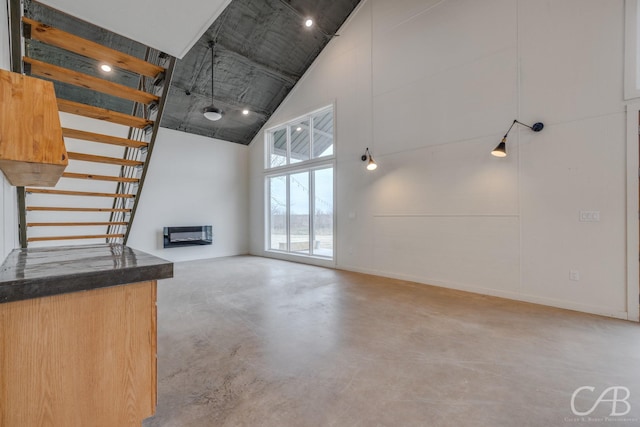 unfurnished living room featuring heating unit and high vaulted ceiling