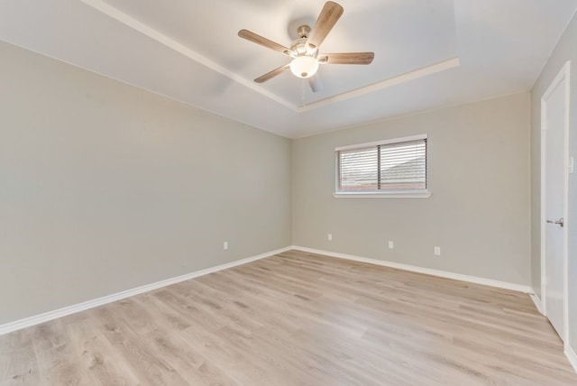 unfurnished room featuring ceiling fan, a tray ceiling, and light hardwood / wood-style flooring