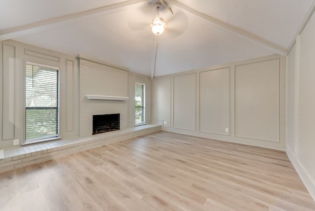 unfurnished living room with lofted ceiling with beams, ceiling fan, a fireplace, and light hardwood / wood-style flooring