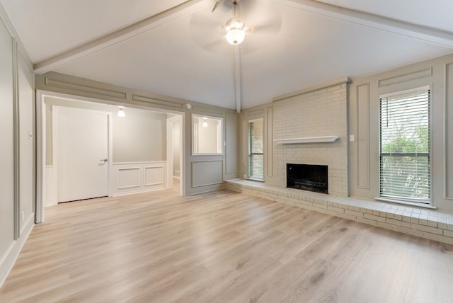 unfurnished living room with vaulted ceiling with beams, light hardwood / wood-style flooring, a fireplace, and ceiling fan