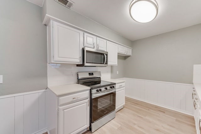 kitchen featuring stainless steel appliances, white cabinetry, backsplash, and light hardwood / wood-style flooring