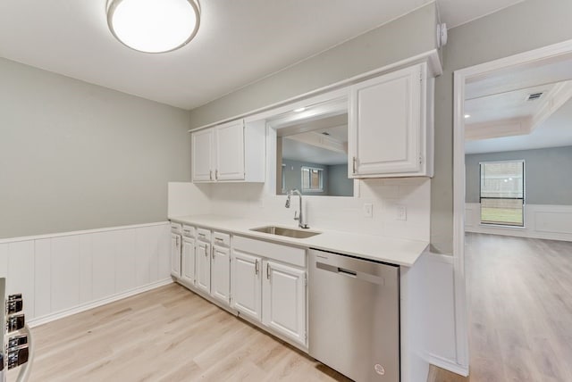 kitchen with sink, white cabinetry, light wood-type flooring, stainless steel dishwasher, and decorative backsplash