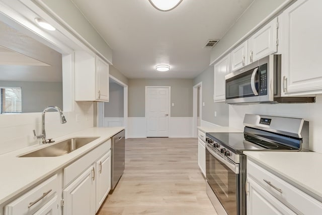 kitchen with white cabinetry, appliances with stainless steel finishes, light hardwood / wood-style floors, and sink