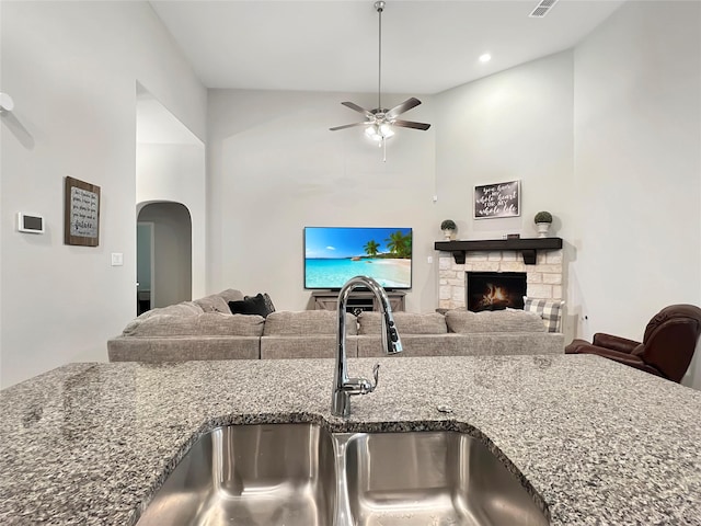 kitchen featuring stone counters, ceiling fan, sink, and a fireplace