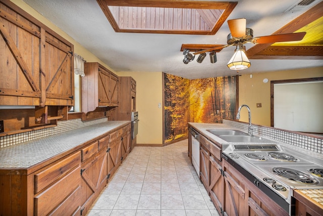 kitchen featuring sink, backsplash, light tile patterned floors, white dishwasher, and cooktop