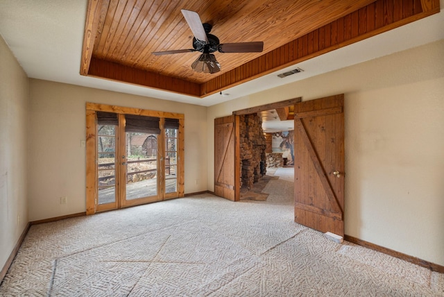 unfurnished room featuring wood ceiling, a tray ceiling, light colored carpet, and ceiling fan