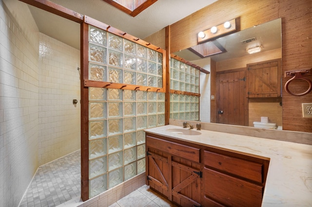 bathroom with a tile shower, vanity, tile patterned floors, and toilet